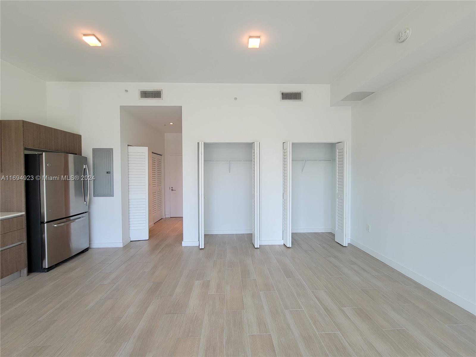 1600 Southwest 1st Avenue, Unit 411 Miami, FL 33129 - Photo 7 of 15 an empty room with wooden floor and a refrigerator