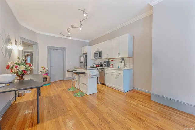 a living room with kitchen island granite countertop wooden floor and white cabinets