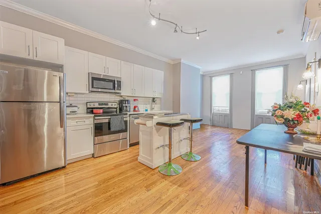 a kitchen with stainless steel appliances granite countertop a refrigerator a stove top oven a sink dishwasher and white cabinets with wooden floor