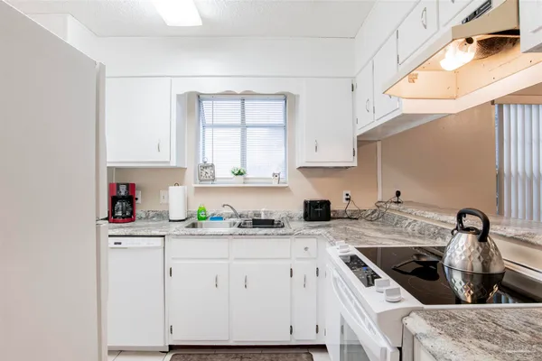 a kitchen with granite countertop a sink a stove and cabinets