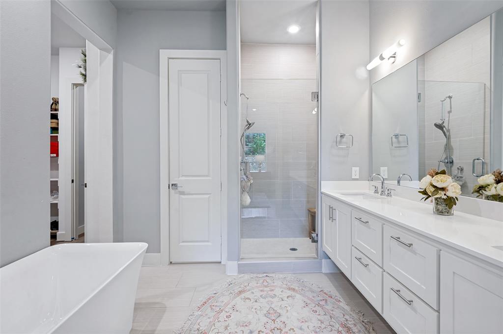 15875 Spectrum Drive, Unit 1101 Addison, TX 75001 - Photo 23 of 37 Freestanding soaking tub, glass-enclosed shower with tiled surround, double vanity with white cabinetry, polished chrome fixtures, and a large wall-mounted mirror