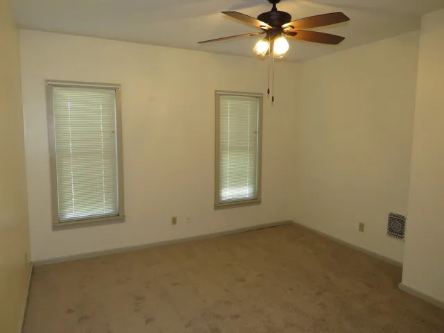 an empty room with windows and fan