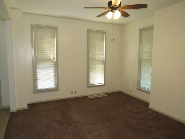 an empty room with a window and a fan