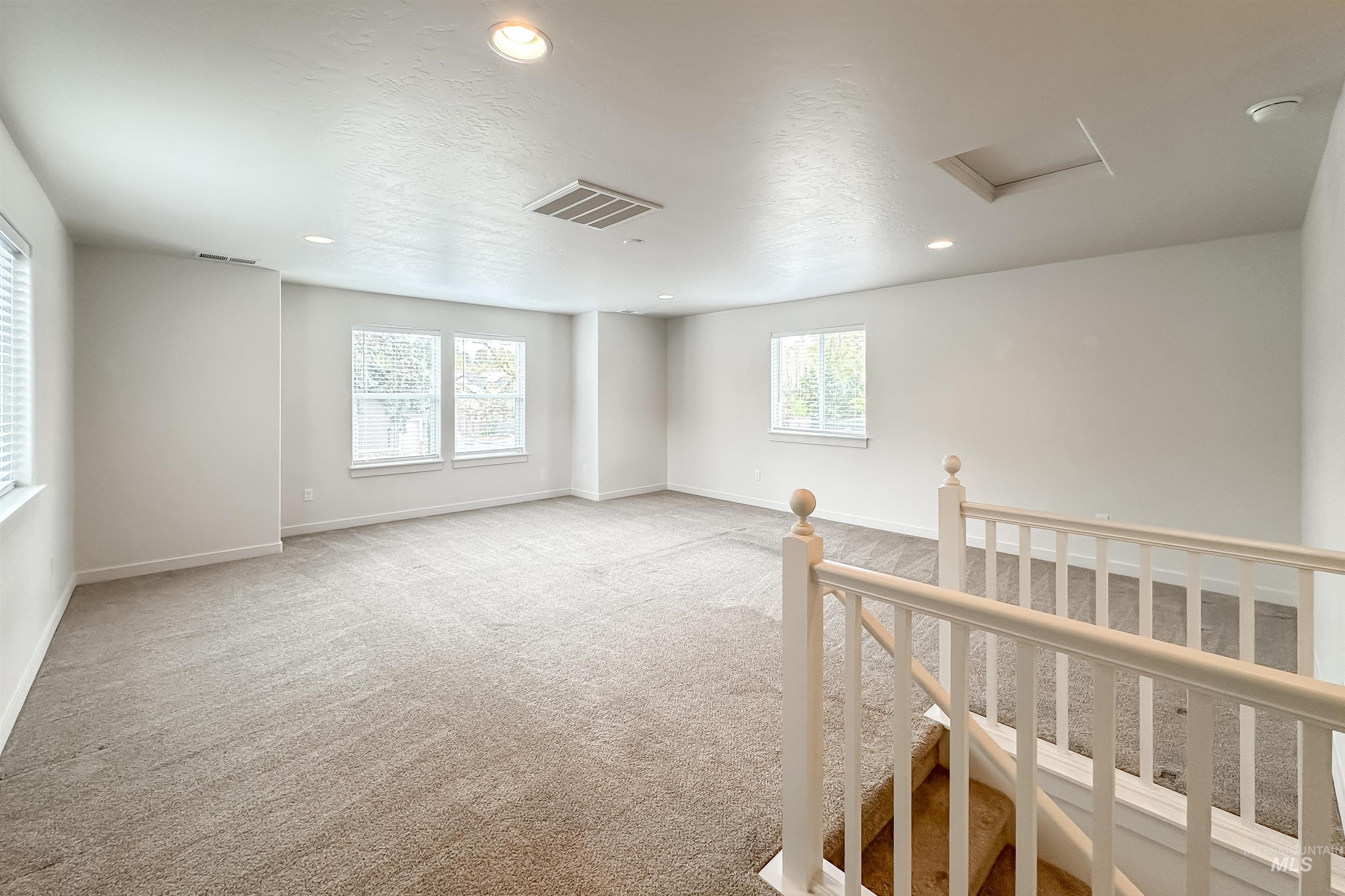 9687 West Arnold Road Boise, ID 83714 - Photo 29 of 37 Expansive carpeted area with multiple windows, recessed lighting, and a painted wood banister