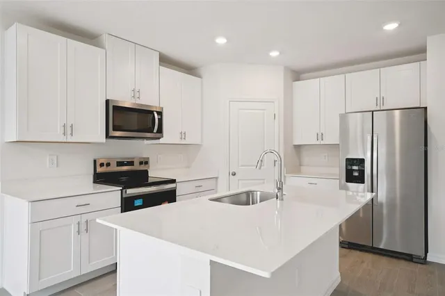 a kitchen with stainless steel appliances a microwave a sink and refrigerator