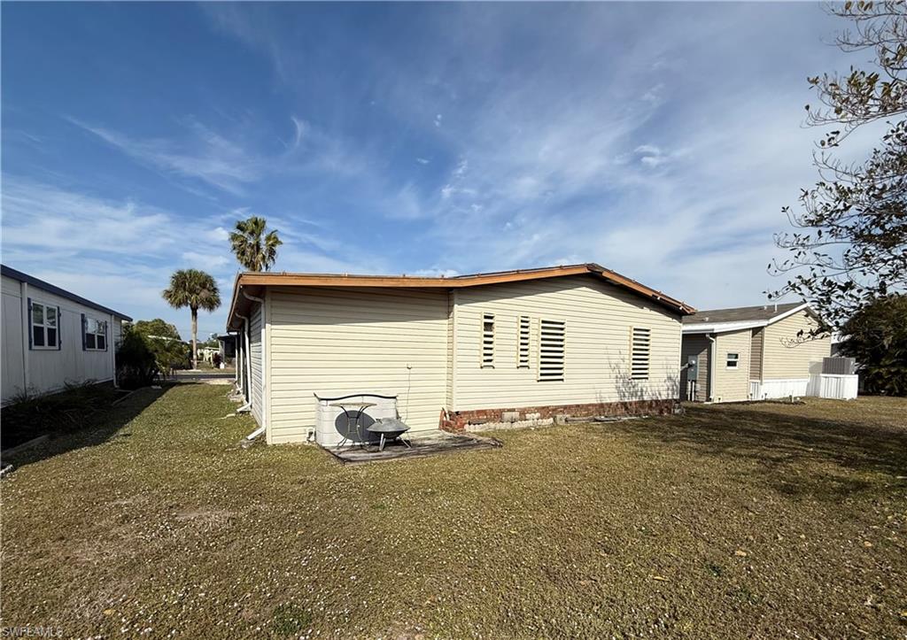 76 Atlantic Way, Unit 76 Naples, FL 34104 - Photo 12 of 18 View of home's exterior featuring a lawn and a patio