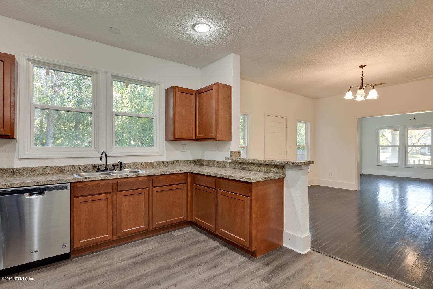 9301 Joos Road Jacksonville, FL 32220 - Photo 19 of 37 a kitchen with granite countertop wooden cabinets a sink and dishwasher with wooden floor