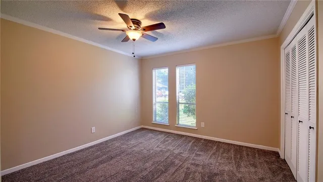 an empty room with windows and fan
