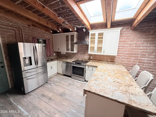 a kitchen with granite countertop stainless steel appliances a counter space a sink and cabinets