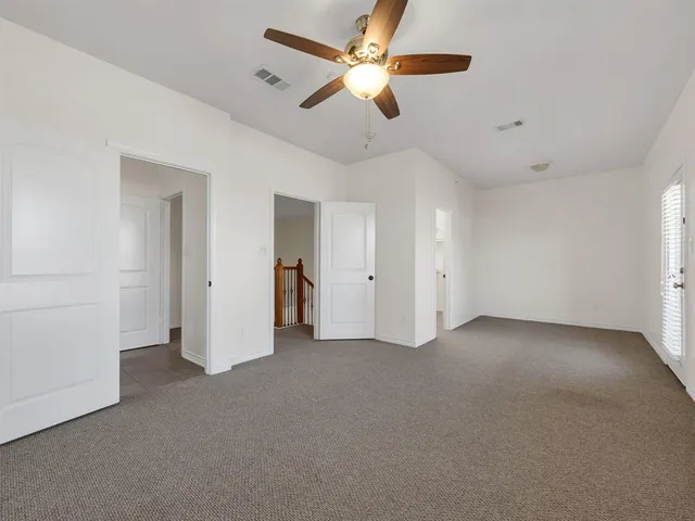 an empty room with chandelier fan and ceiling fan
