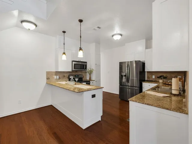 a kitchen with stainless steel appliances granite countertop a sink a stove a refrigerator and island with wooden floor