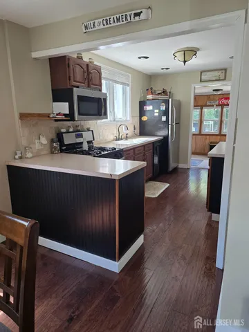 a kitchen with stainless steel appliances granite countertop a stove a sink dishwasher and a microwave oven with wooden floor