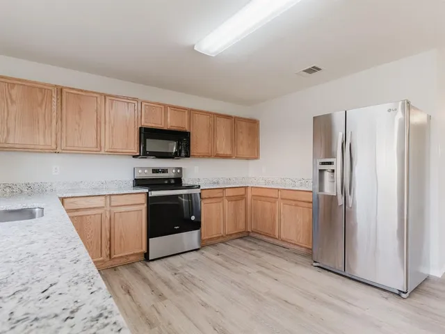 a kitchen with granite countertop a refrigerator stove top oven and sink