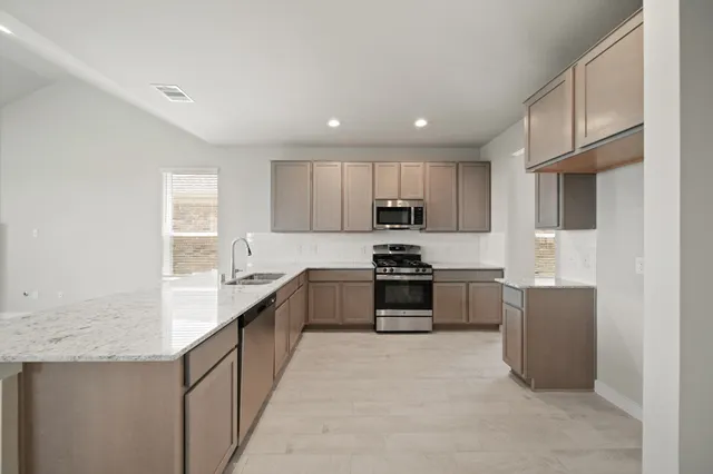 a kitchen with stainless steel appliances kitchen island granite countertop a refrigerator and a sink