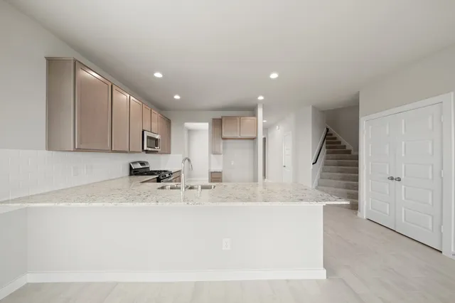 a large kitchen with stainless steel appliances granite countertop a sink and cabinets with wooden floor