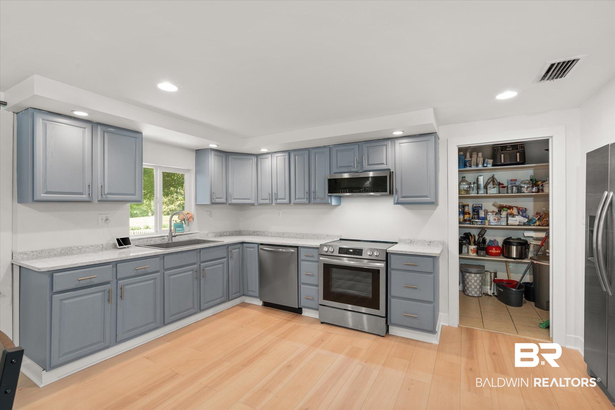 529 Cleveland Road Saraland, AL 36571 - Photo 6 of 31 Kitchen featuring light wood-style flooring, gray cabinetry, visible vents, stainless steel appliances, and a sink