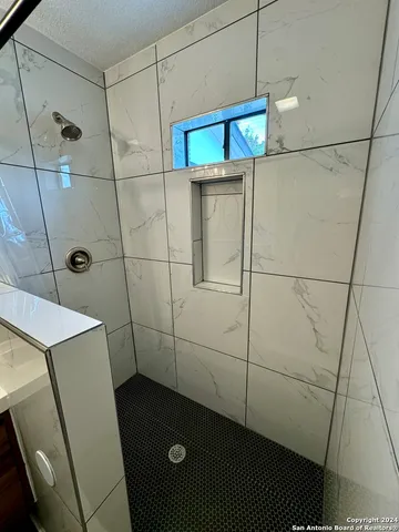 a bathroom with a shower and a tiled wall