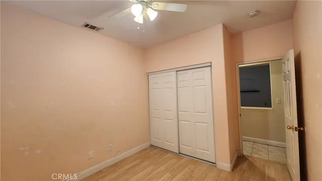 an empty room with wooden floor closet and windows