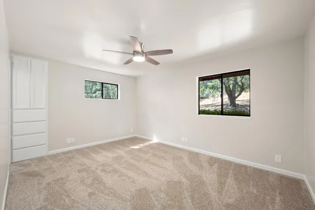 an empty room with a ceiling fan and window