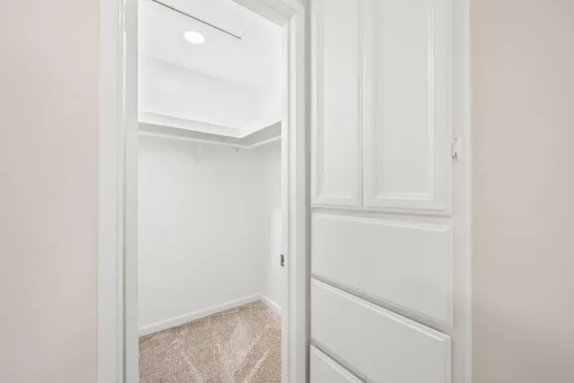 an empty room with chandelier fan and windows