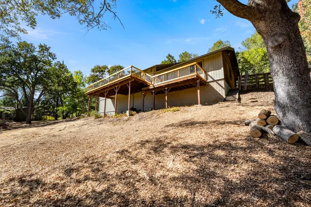 an aerial view of a house with yard and covered with trees
