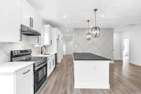 a kitchen with a stove a sink a refrigerator and chairs