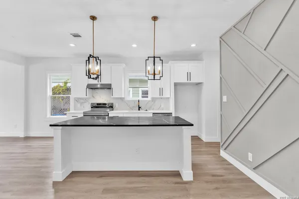 a kitchen with stainless steel appliances granite countertop a sink a refrigerator and wooden floor