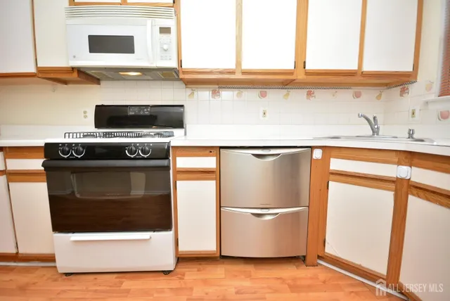 a kitchen with stainless steel appliances a stove and white cabinets