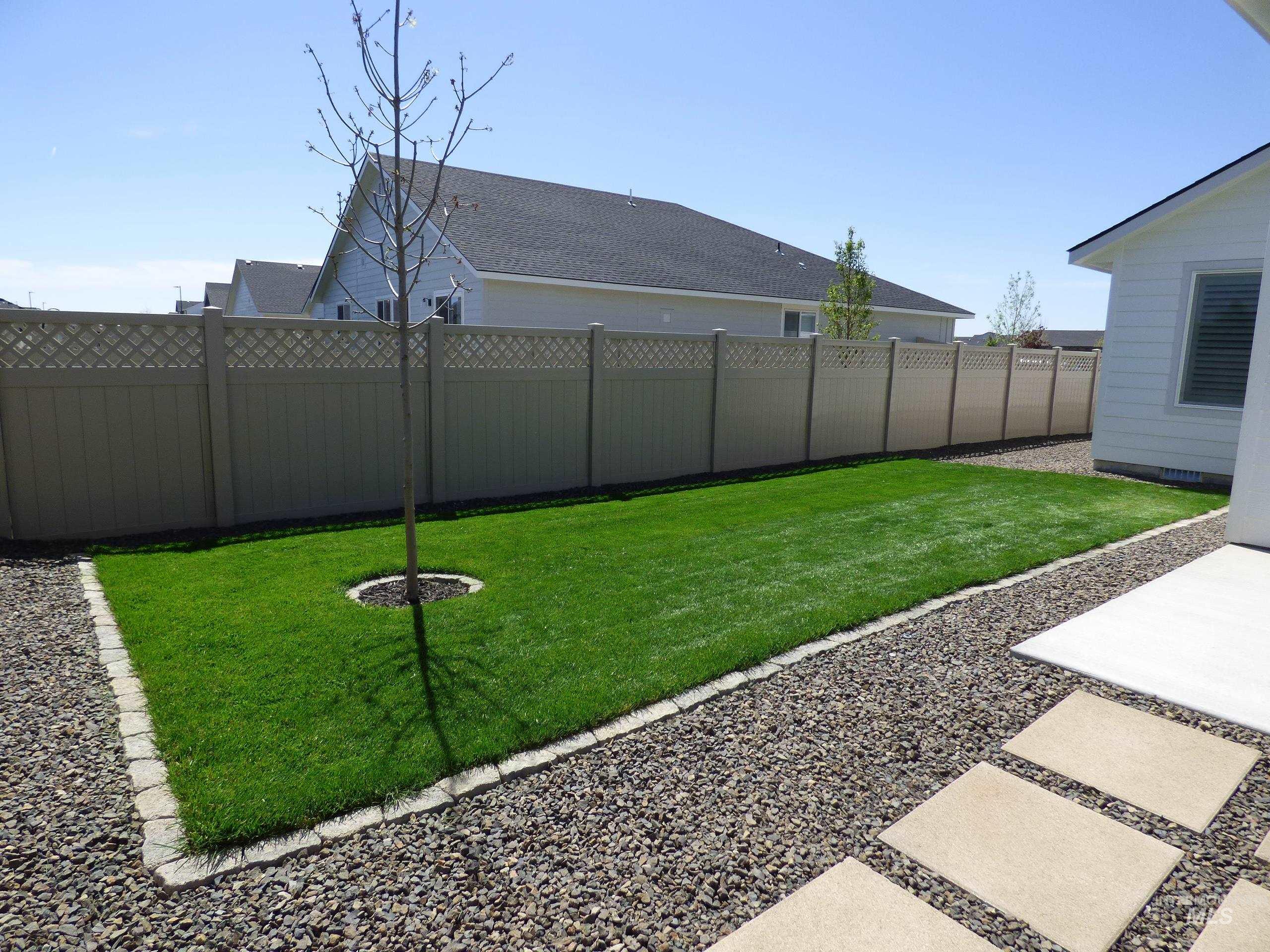 2708 East Buckaroo Drive Kuna, ID 83634 - Photo 40 of 48 Expansive backyard featuring a manicured lawn, gravel landscaping, a young tree, and a concrete patio with stepping stones