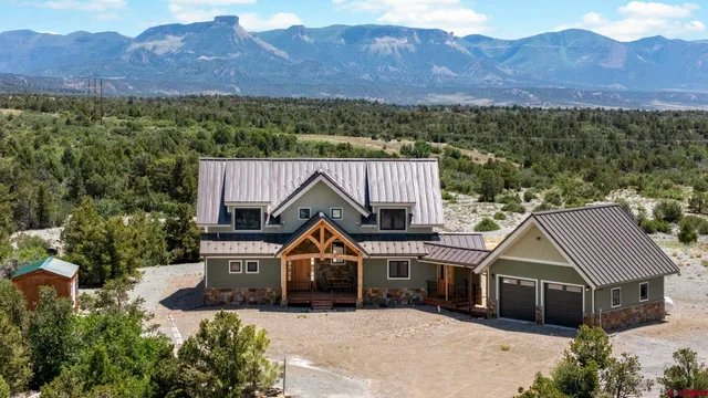 a front view of a house with a yard and mountain view in back