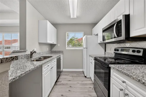 a kitchen with stainless steel appliances granite countertop a stove microwave and sink