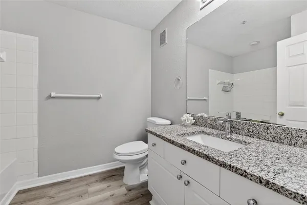 a bathroom with a granite countertop sink a toilet and a mirror