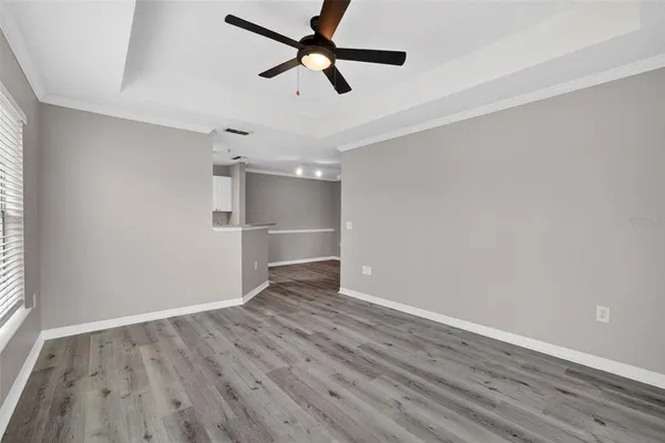 an empty room with wooden floor ceiling fan and windows