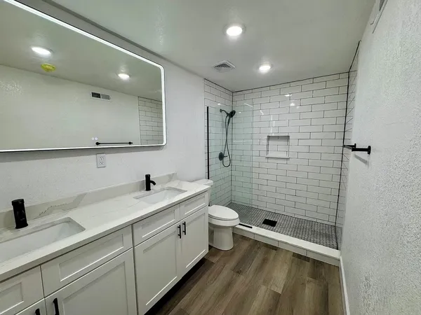 a bathroom with a double vanity sink toilet and shower