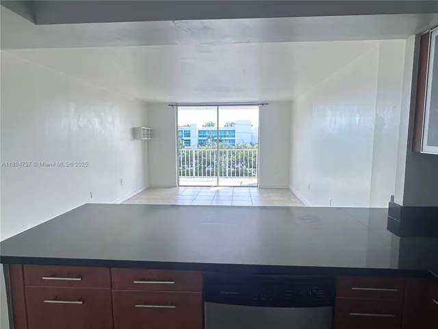 a view of empty room with kitchen
