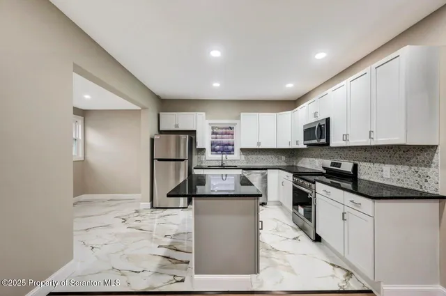 a kitchen with stainless steel appliances granite countertop a refrigerator a sink a stove a microwave and white cabinets