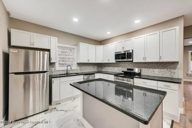 a kitchen with granite countertop a sink and white cabinets