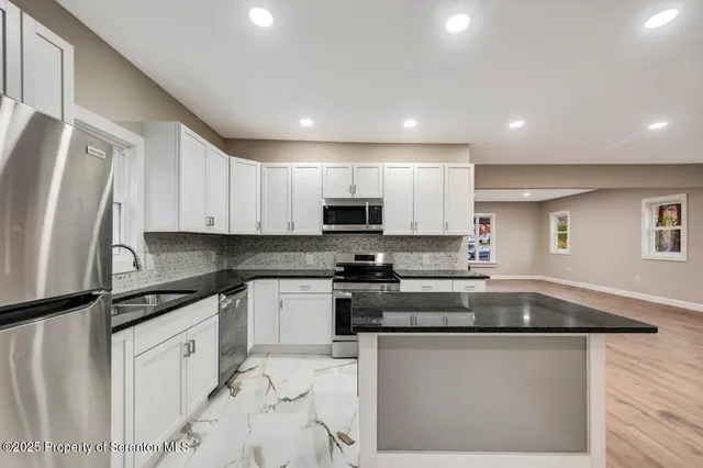 a kitchen with granite countertop a sink and stainless steel appliances