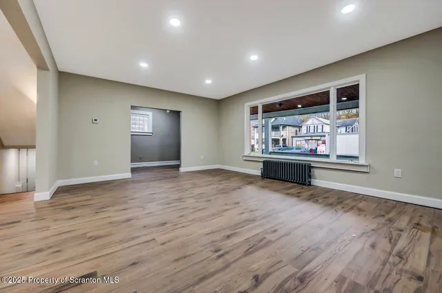 a view of an empty room with kitchen and window