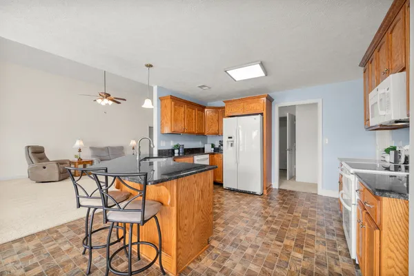 a kitchen with stainless steel appliances kitchen island granite countertop a stove a sink a dining table and chairs with wooden floor