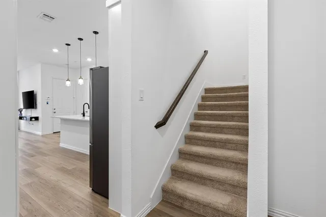 a view of a hallway with stairs and a chandelier