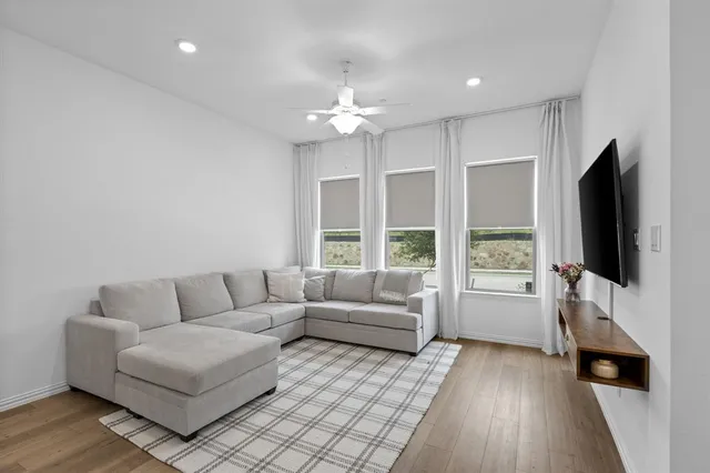 a living room with furniture a flat screen tv and a floor to ceiling window