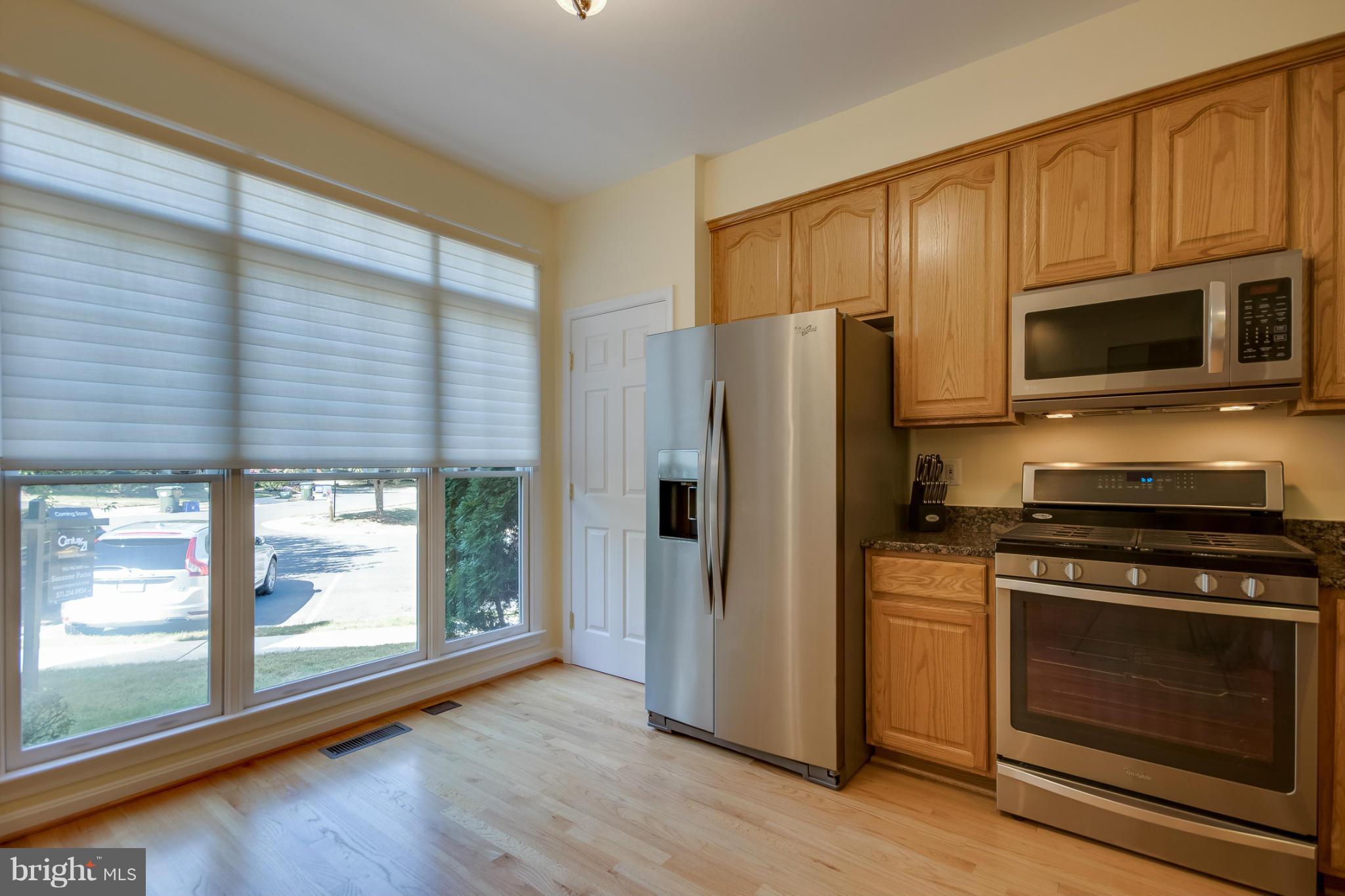 1279 Weatherstone Court Reston, VA 20194 - Photo 3 of 28 a kitchen with stainless steel appliances a stove a microwave and cabinets