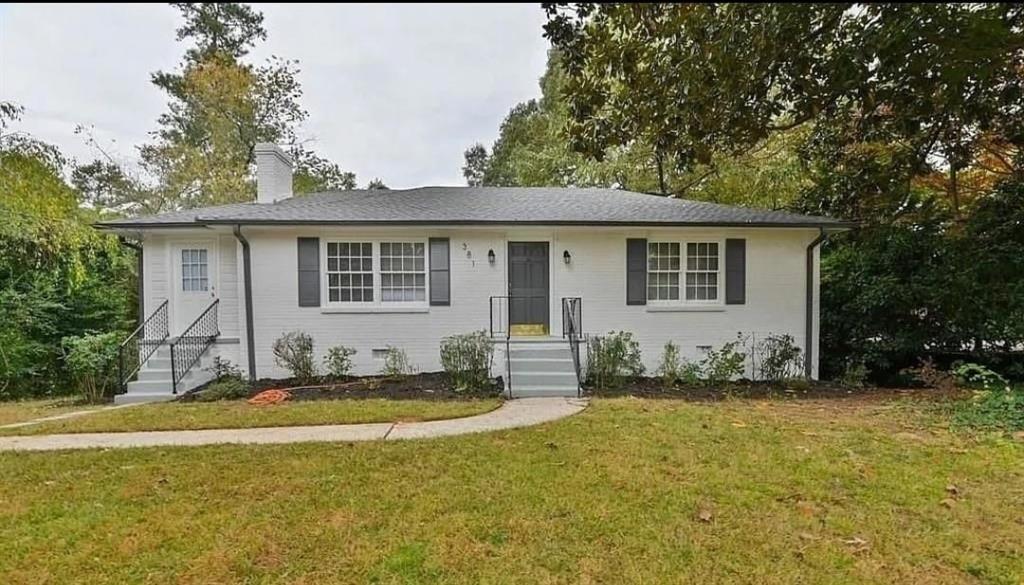 a front view of house with yard and trees in the background