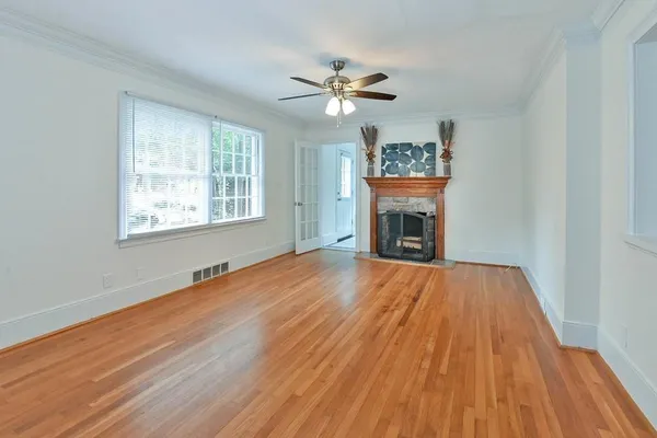 a view of an empty room with wooden floor fireplace and a window