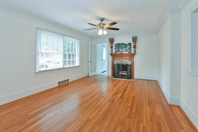 a view of an empty room with wooden floor fireplace and a window