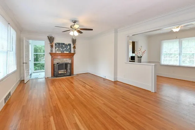 a view of empty room with wooden floor and fan