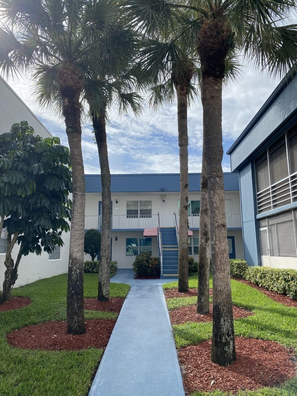 a front view of a house with a garden and trees