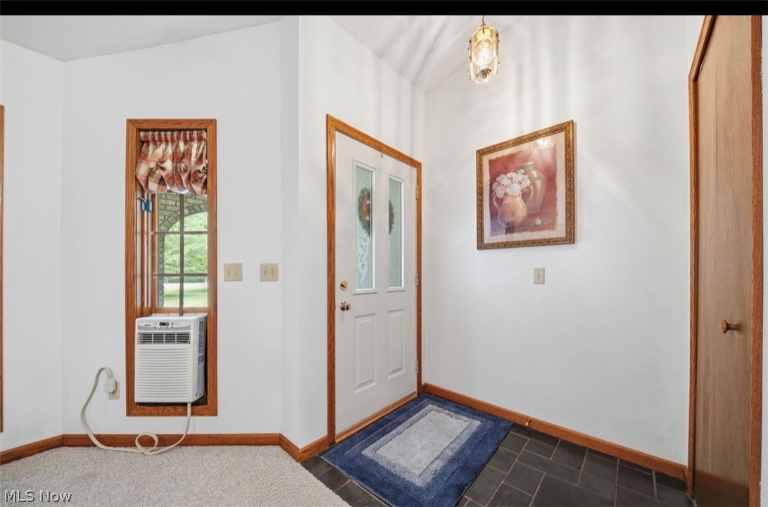 3556 Lake Road Conneaut, OH 44030 - Photo 8 of 39 Entryway featuring a white paneled door with decorative glass, dark tile flooring, wood-finish baseboards, and a recessed window with wood-finish trim