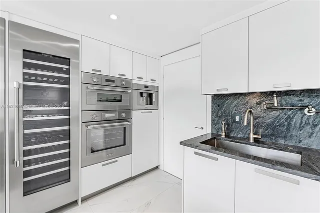 a kitchen with white cabinets and appliances